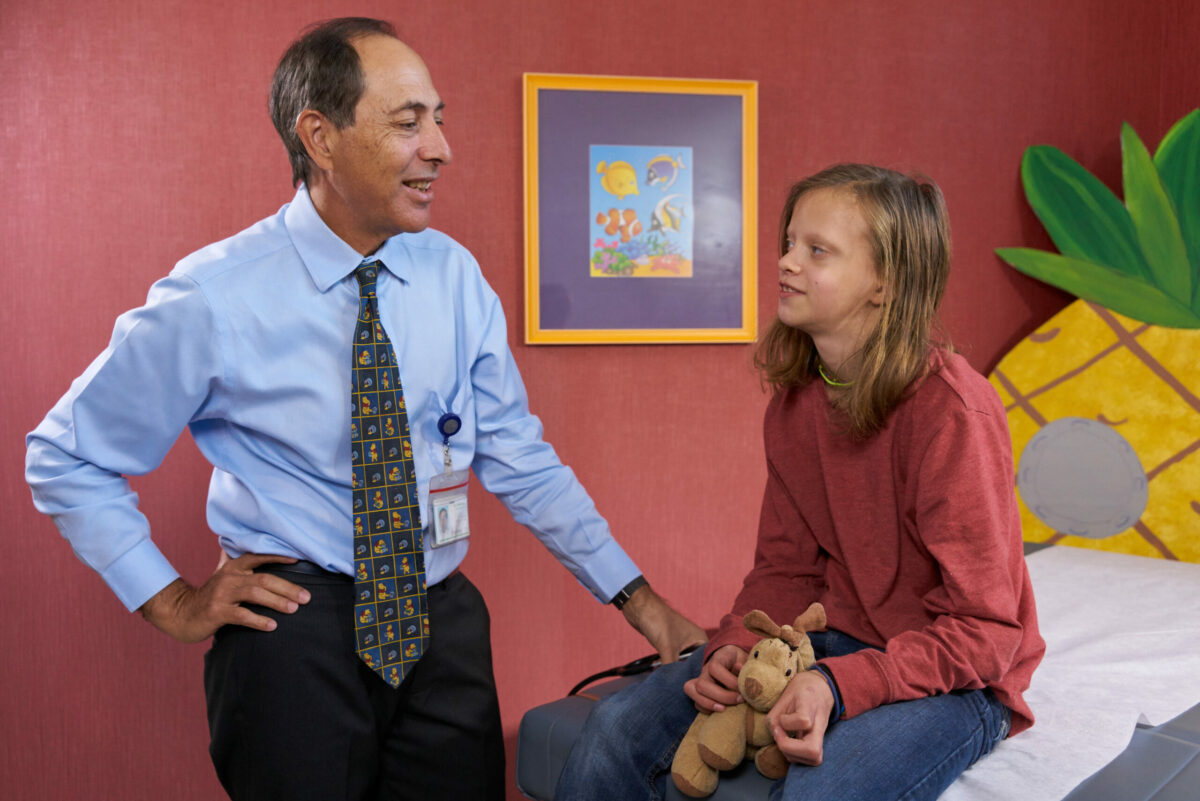 Pediatric heart doctor talking to patient in an exam room.