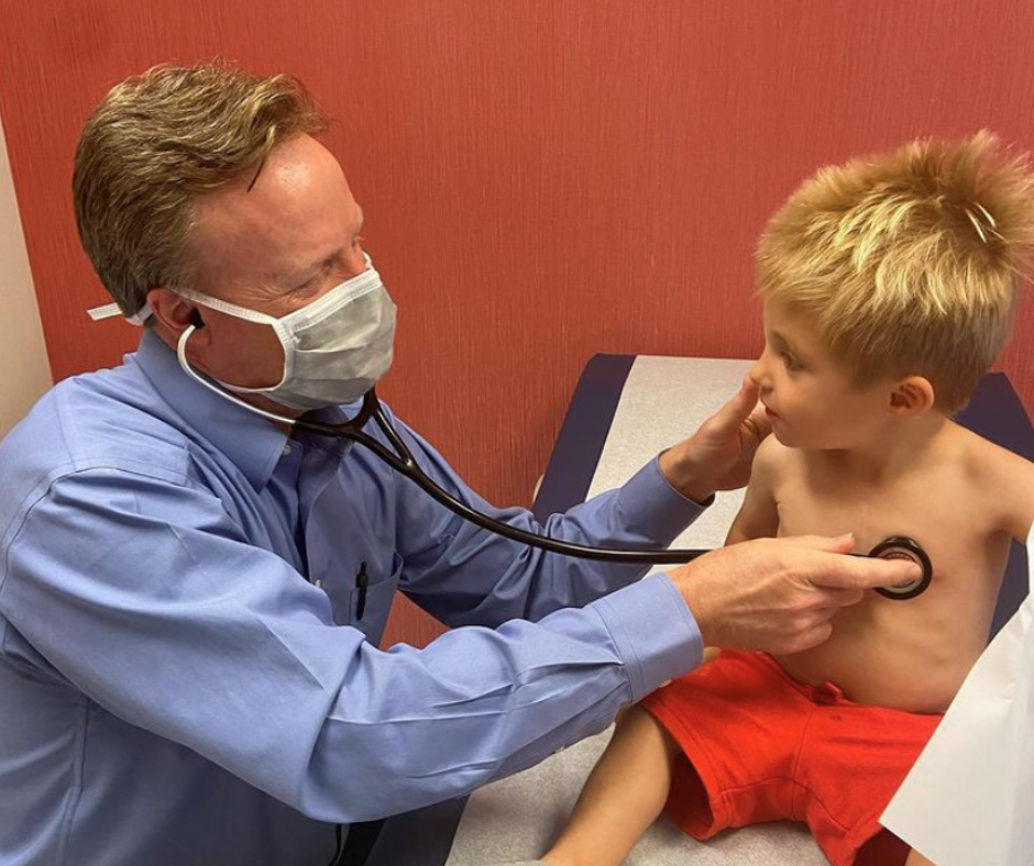 Pediatric cardiologist listening to child heart.